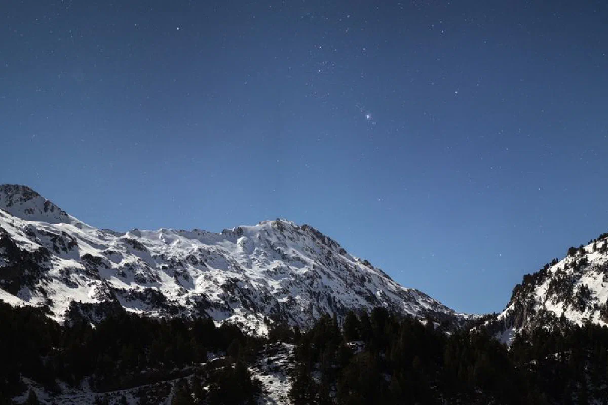 Majestic snowy mountain under a starry night sky, showcasing winter beauty.