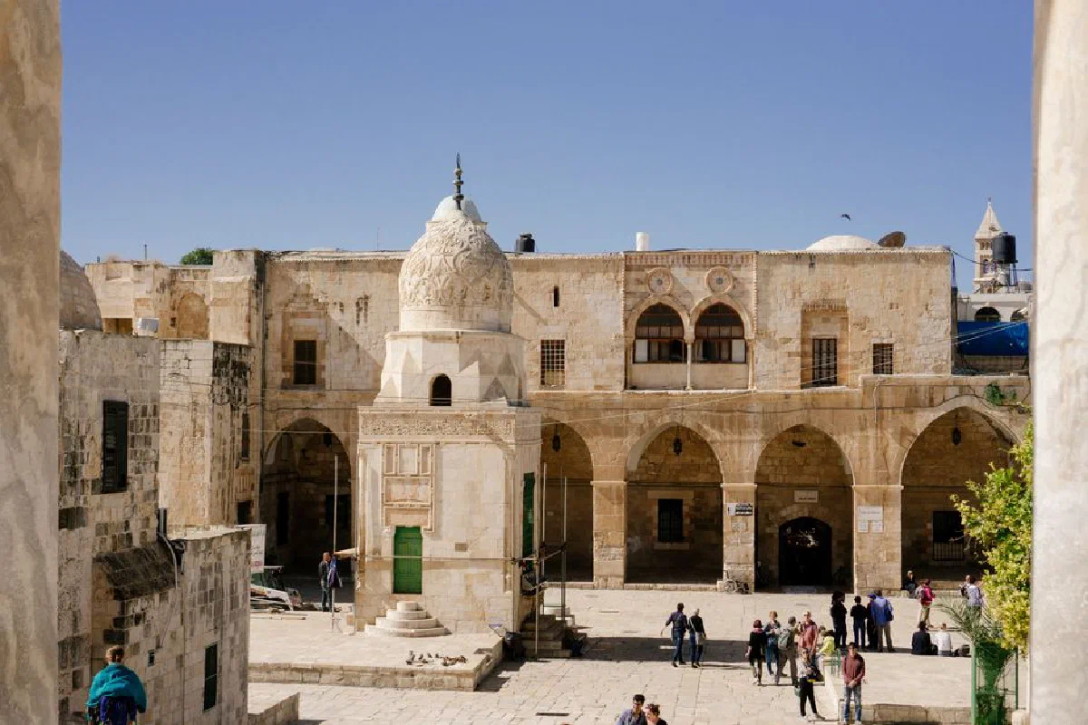 Stone buildings and arches in the Old City of Jerusalem with people exploring the historic site.