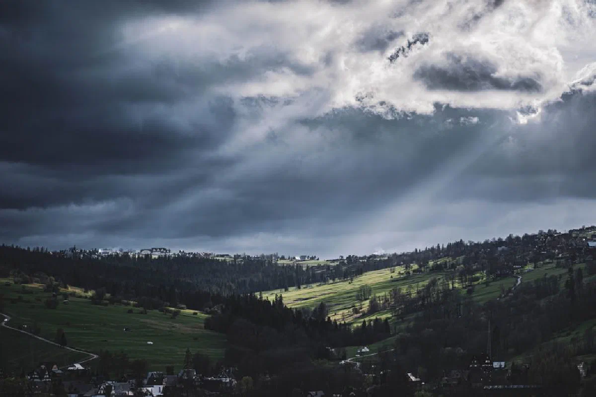Moody landscape of Biały Dunajec, Poland, with dramatic clouds and sunlight breaking through.