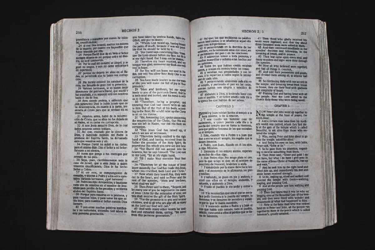 An open Bible displaying chapters of Acts in Spanish and English, photographed from above.