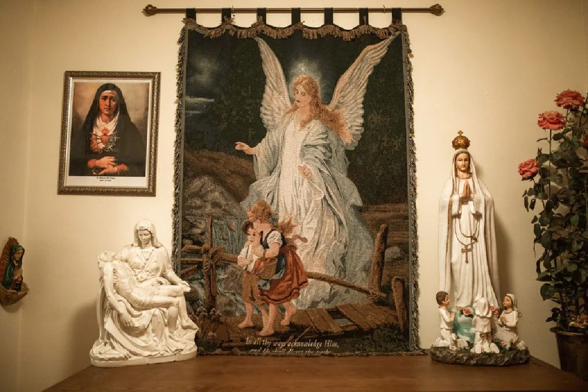 A sacred indoor altar featuring an angelic tapestry, religious statues, and flowers, exuding faith and serenity.