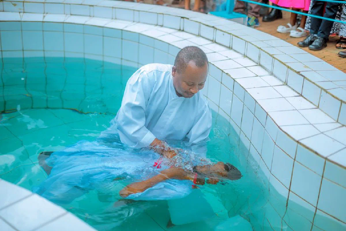 A baptism ceremony conducted by a man in a pool, symbolizing spiritual renewal.