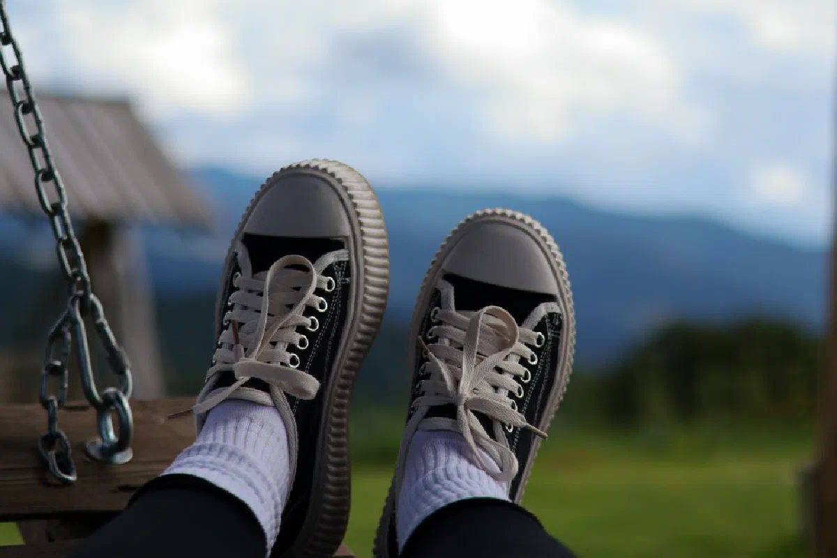 Person relaxing on a swing with feet up, enjoying countryside views.