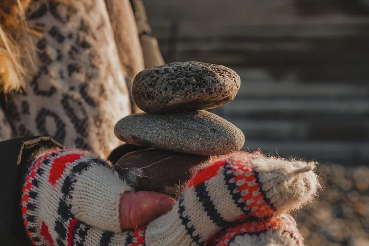 A warm winter moment capturing stacked pebbles held with cozy mittens outdoors.
