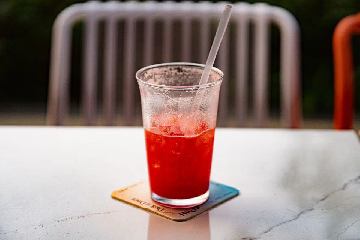 A cool red beverage in a transparent glass with a straw on a table in Ho Chi Minh City, Vietnam.