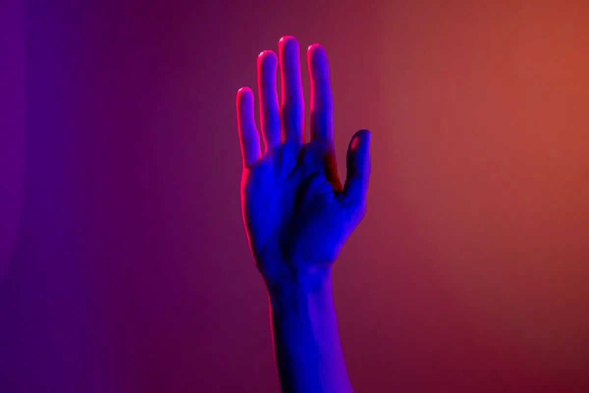 A single hand under neon lighting creating a colorful visual effect.