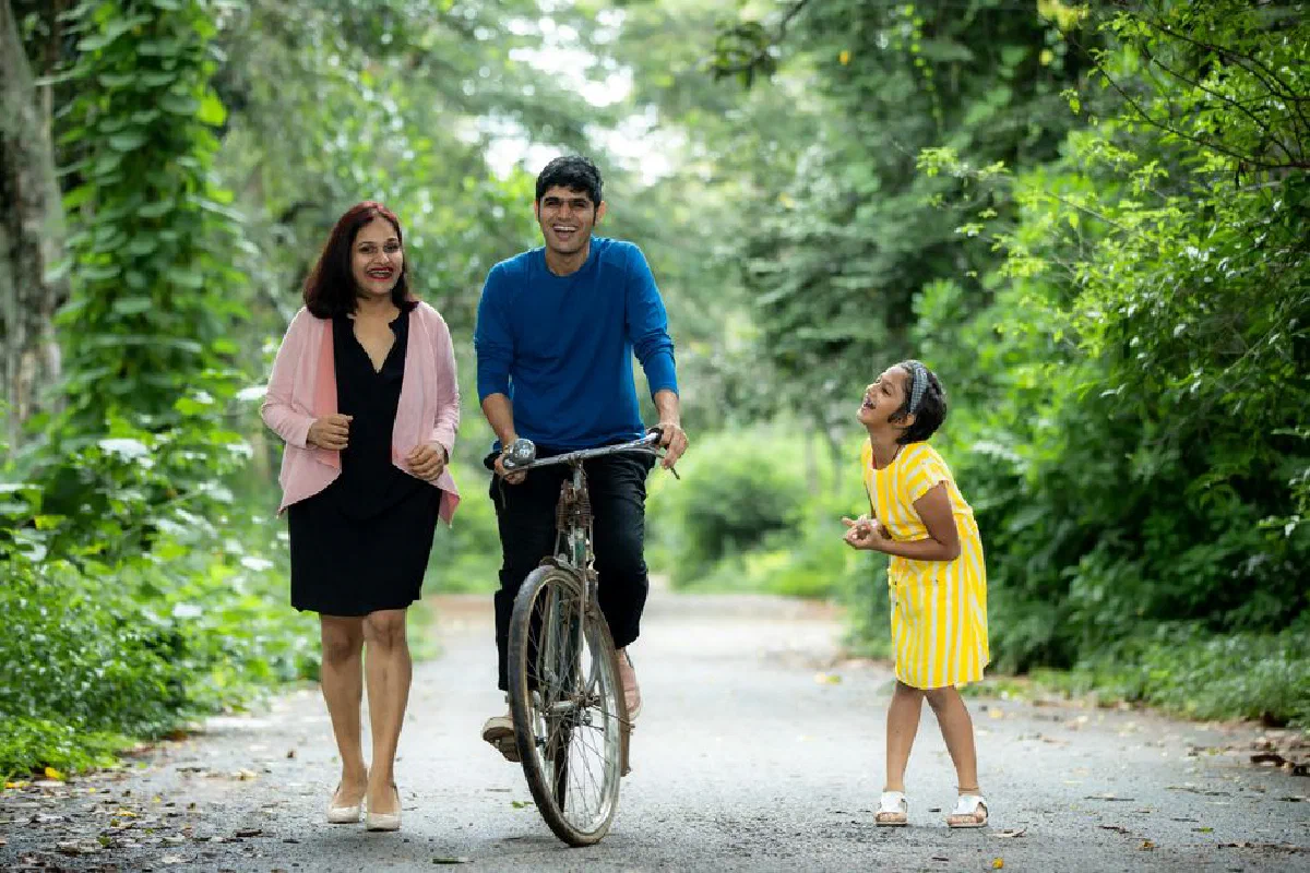 A joyful family enjoying a walk with a bicycle on a green forest path.