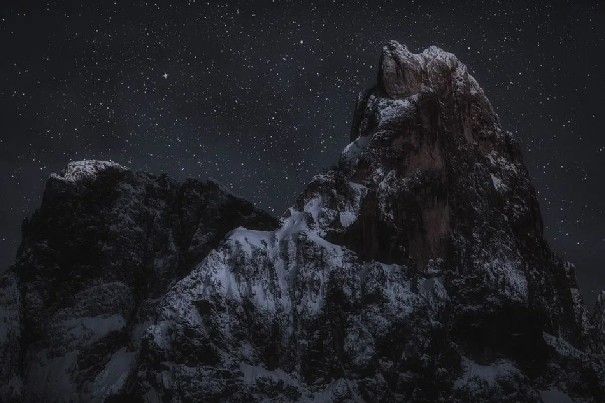 Majestic snow-capped mountain under a serene starry night sky, showcasing natural beauty.