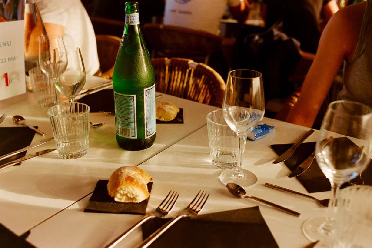 A beautifully arranged dining table in a French café setting, with bread, water, and wine glasses.