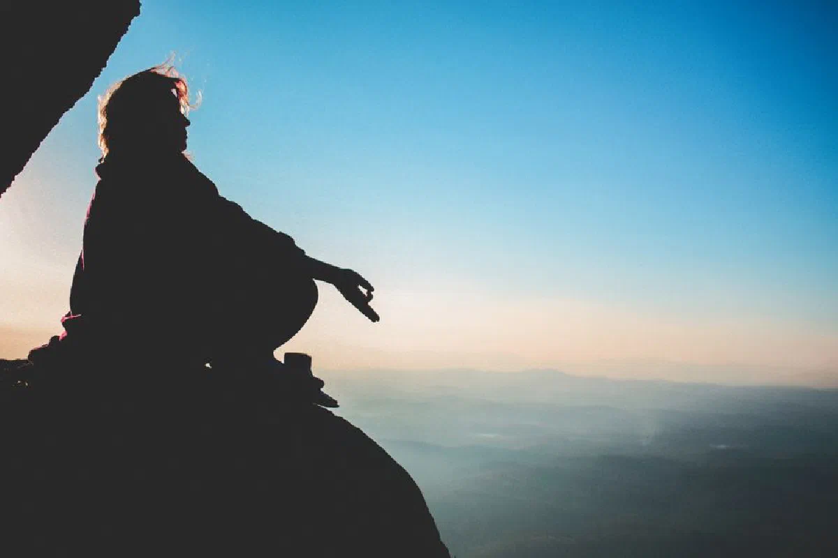 Silhouette of a person meditating on a mountain at sunset in Brazil, exuding peace and tranquility.
