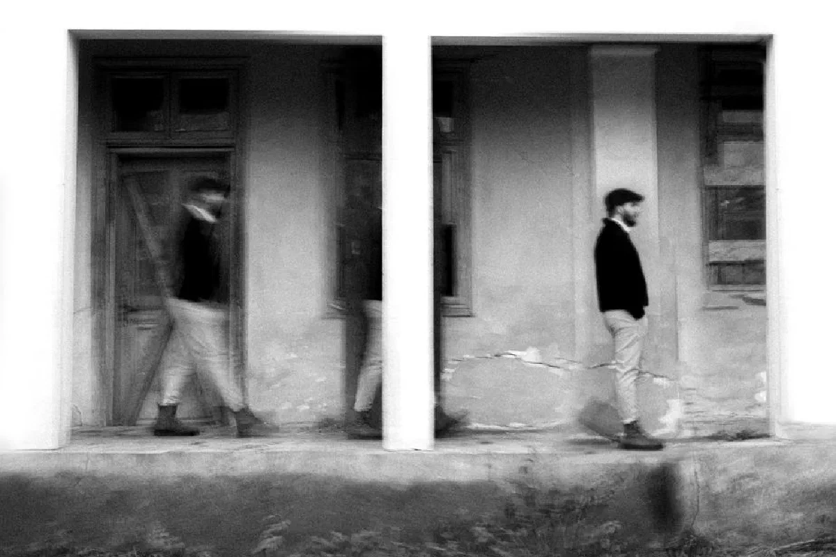 A creative black and white motion blur of a person walking in front of a building.