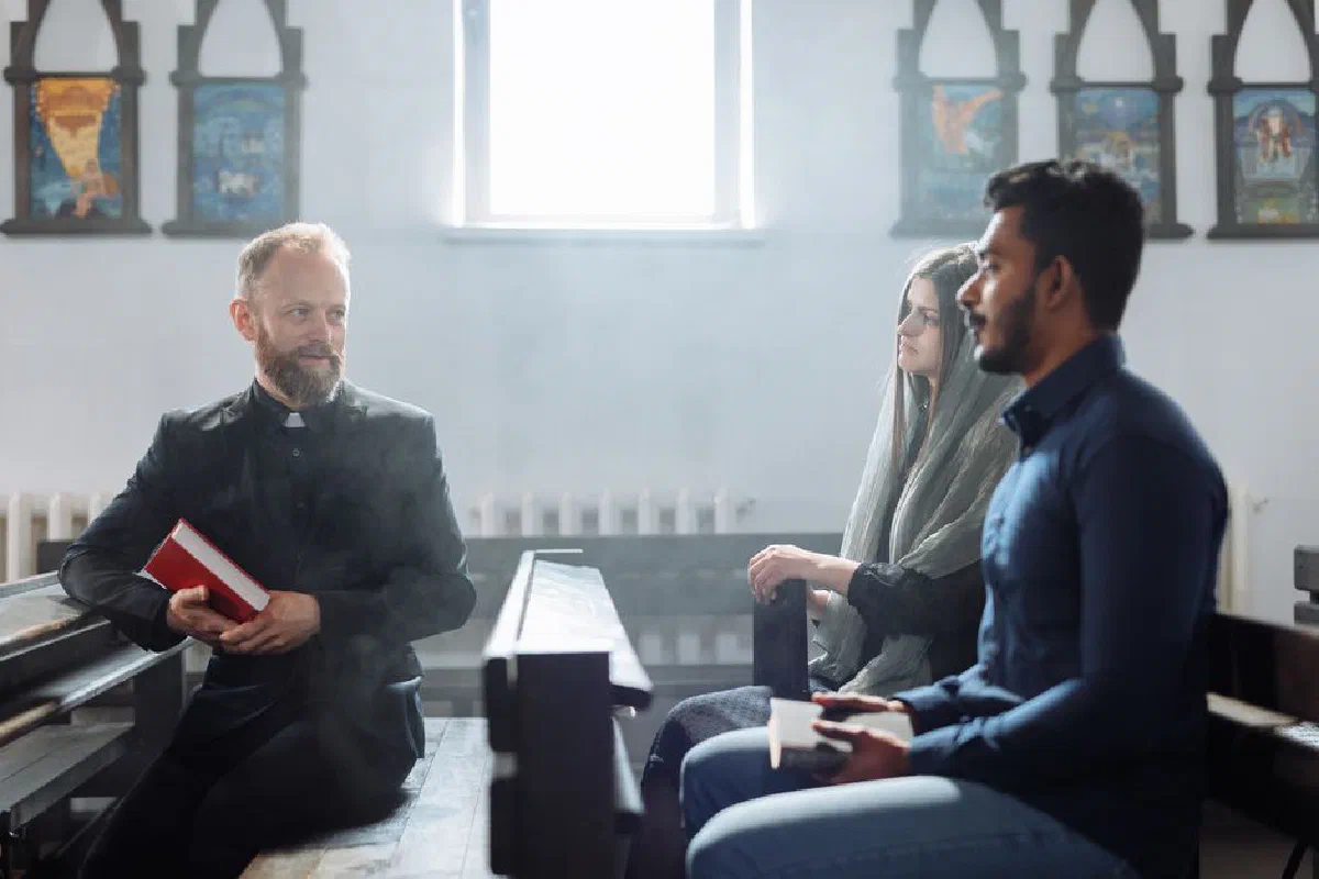 A priest converses with two people inside a church, highlighting religious dialogue and community.