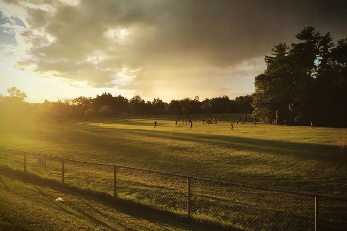 Sunrise over a rural field with people in the distance, showcasing nature and pastoral beauty.