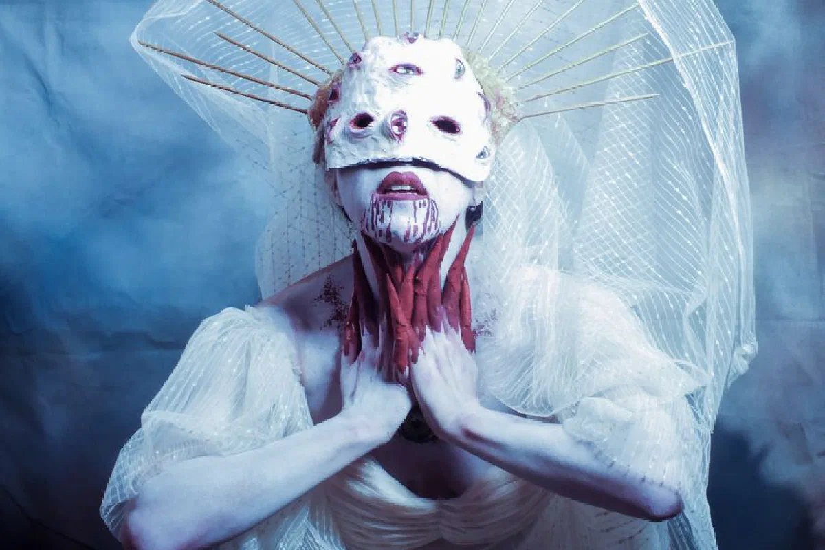 Surreal portrait of a gothic woman in a mask and veil with a dramatic expression.