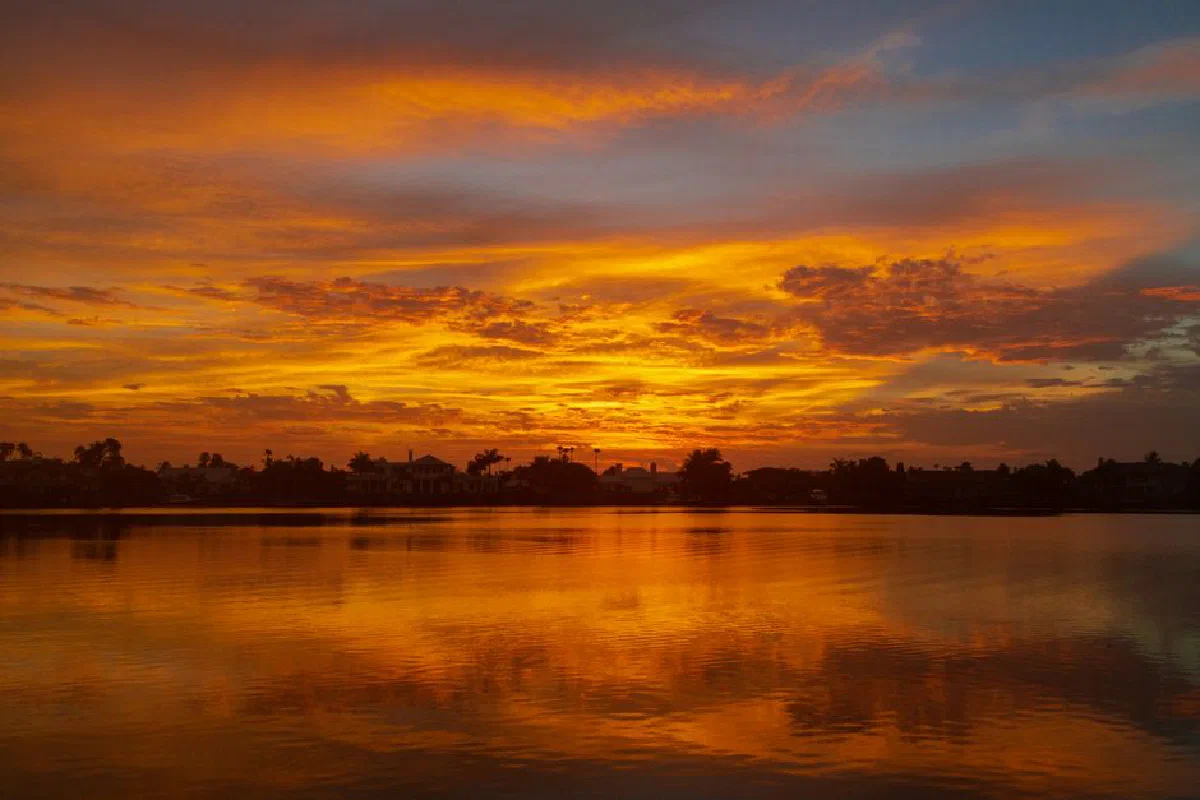 Beautiful sunset reflecting over serene lake with vivid orange and blue skies.