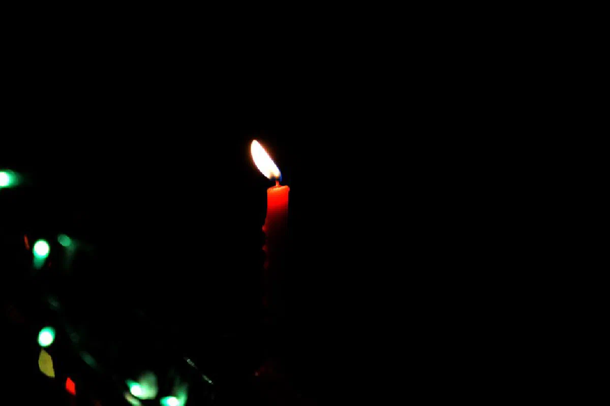 A single red candle burning brightly against a dark background, creating a serene ambiance.
