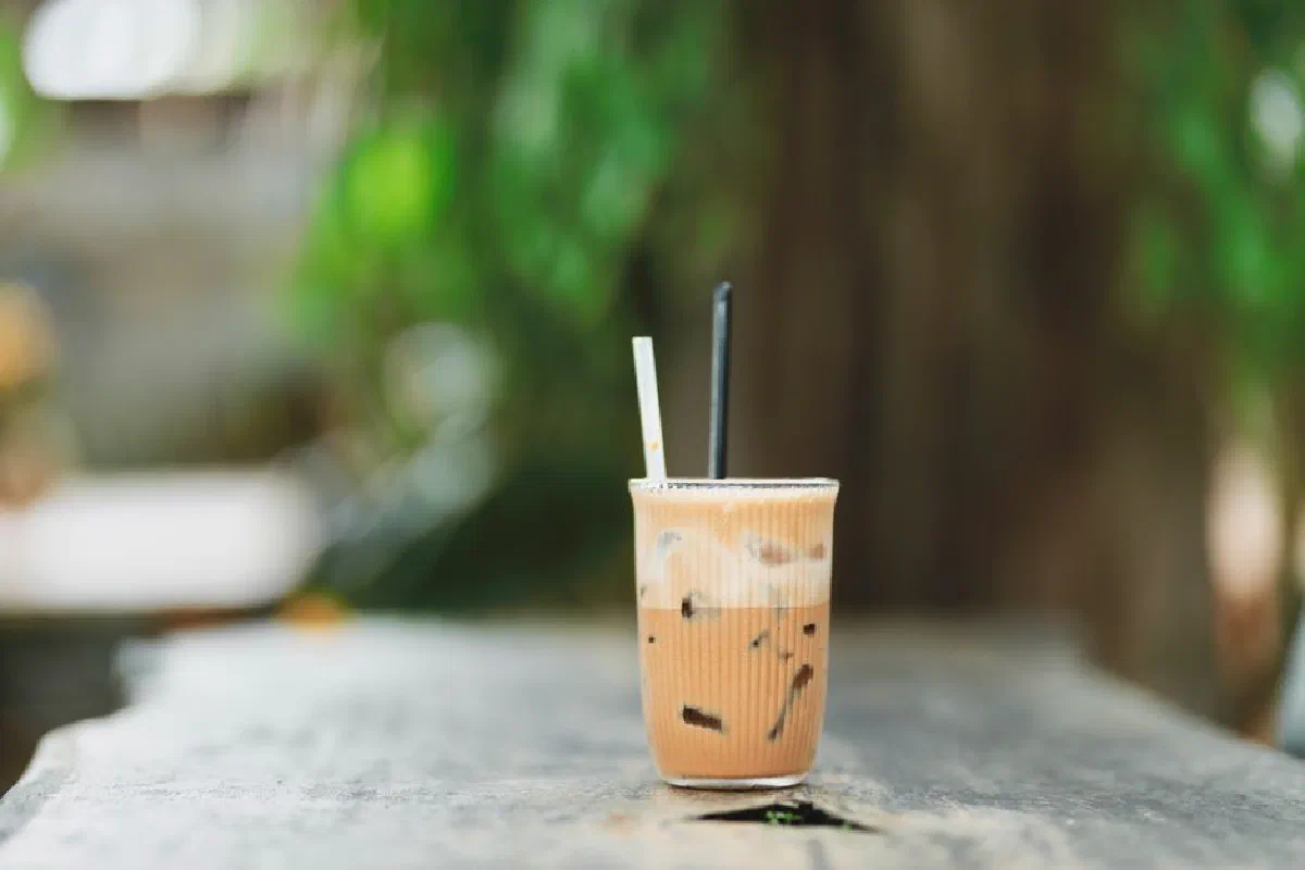 A chilled glass of iced coffee on a sunny outdoor table, ideal for a summer refreshment.