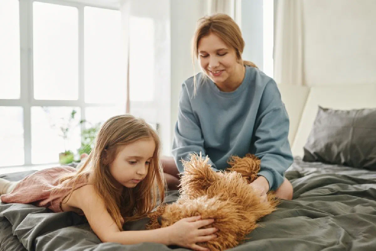 A mother and her daughter enjoying playful moments with their dog at home.