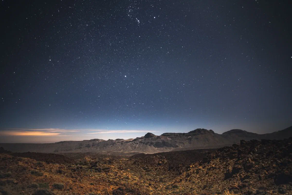 A breathtaking view of a starry night sky over rugged mountains, capturing nature's beauty.