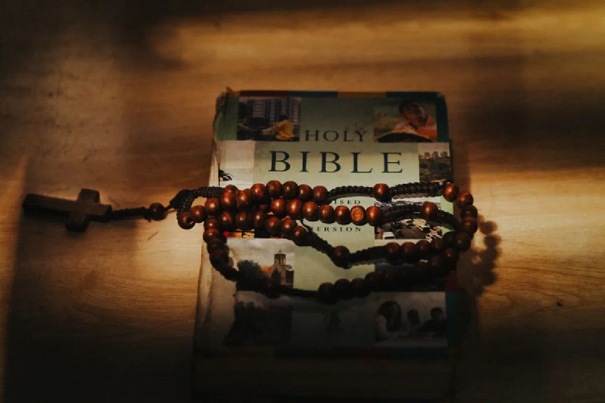 A Bible with rosary beads in warm, dramatic lighting, symbolizing faith.