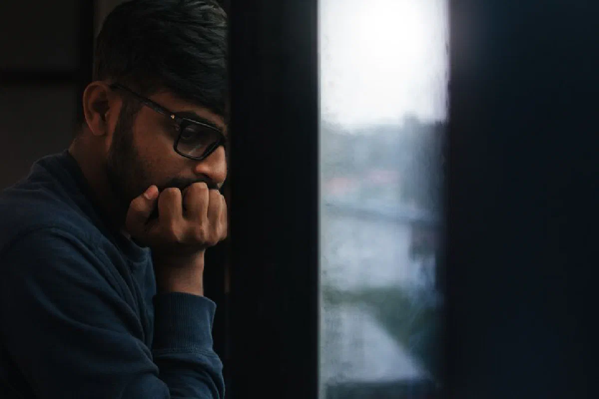 Contemplative man gazing out a rainy window, lost in thought.