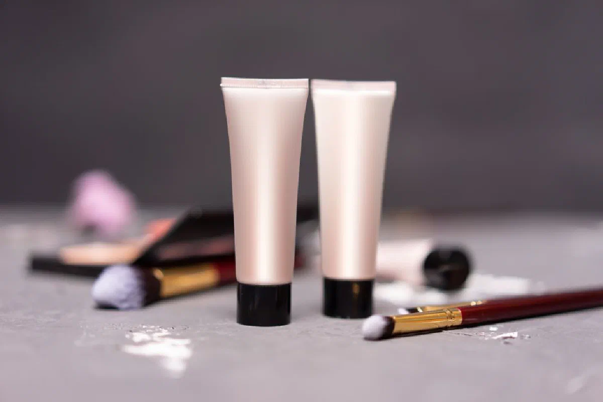 Close-up of skincare tubes with makeup brushes on a table, symbolizing beauty and self-care.