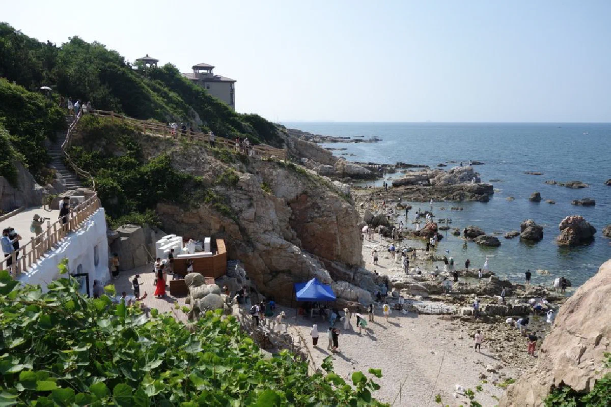 Beautiful coastal scene with rocky beach, people enjoying the ocean on a sunny day.