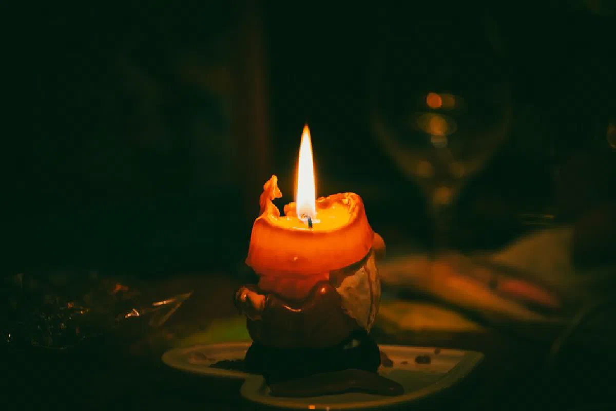 Close-up of a warm, glowing wax candle in the dark, creating a cozy and serene ambiance.