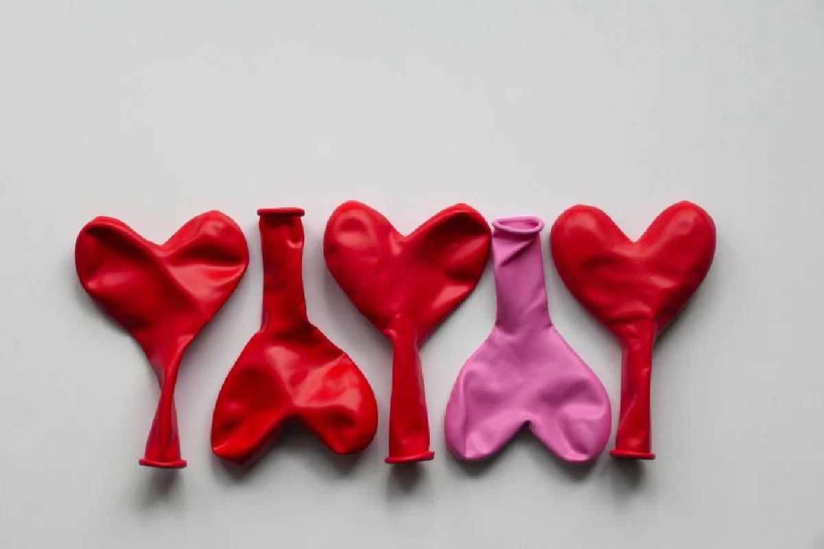 Uninflated red and pink heart-shaped balloons arranged on a white surface, perfect for celebrations.