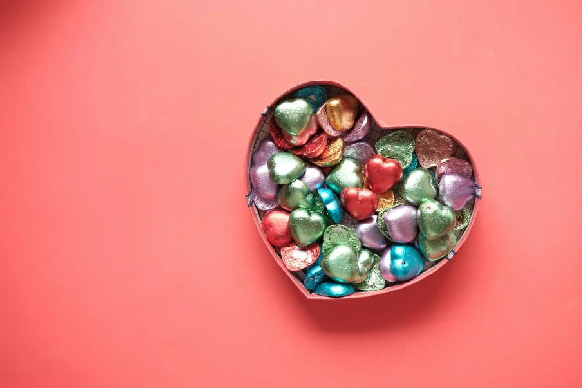 Vibrant heart-shaped chocolates in a heart box on a pink background. Perfect for Valentine's Day.