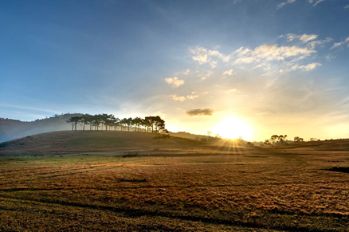Captivating sunrise over a serene countryside landscape with hills and trees.