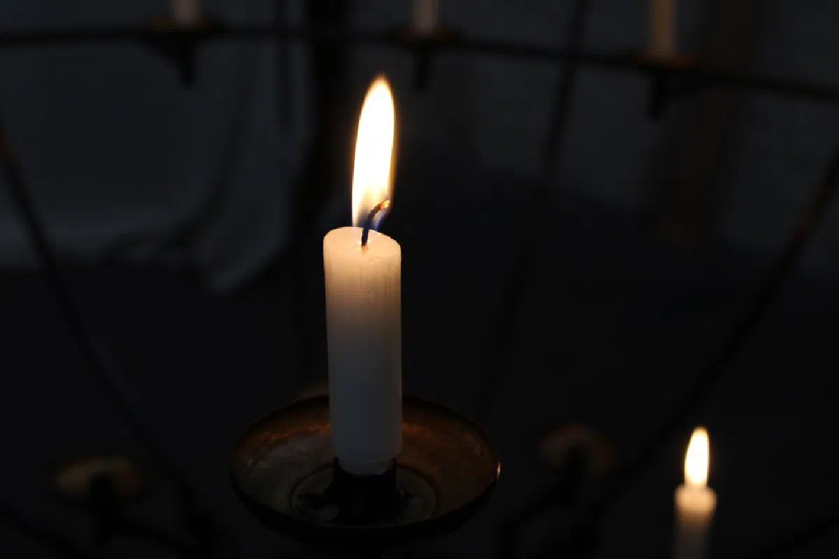 A serene close-up of a burning candle on a candle holder, casting a warm glow.