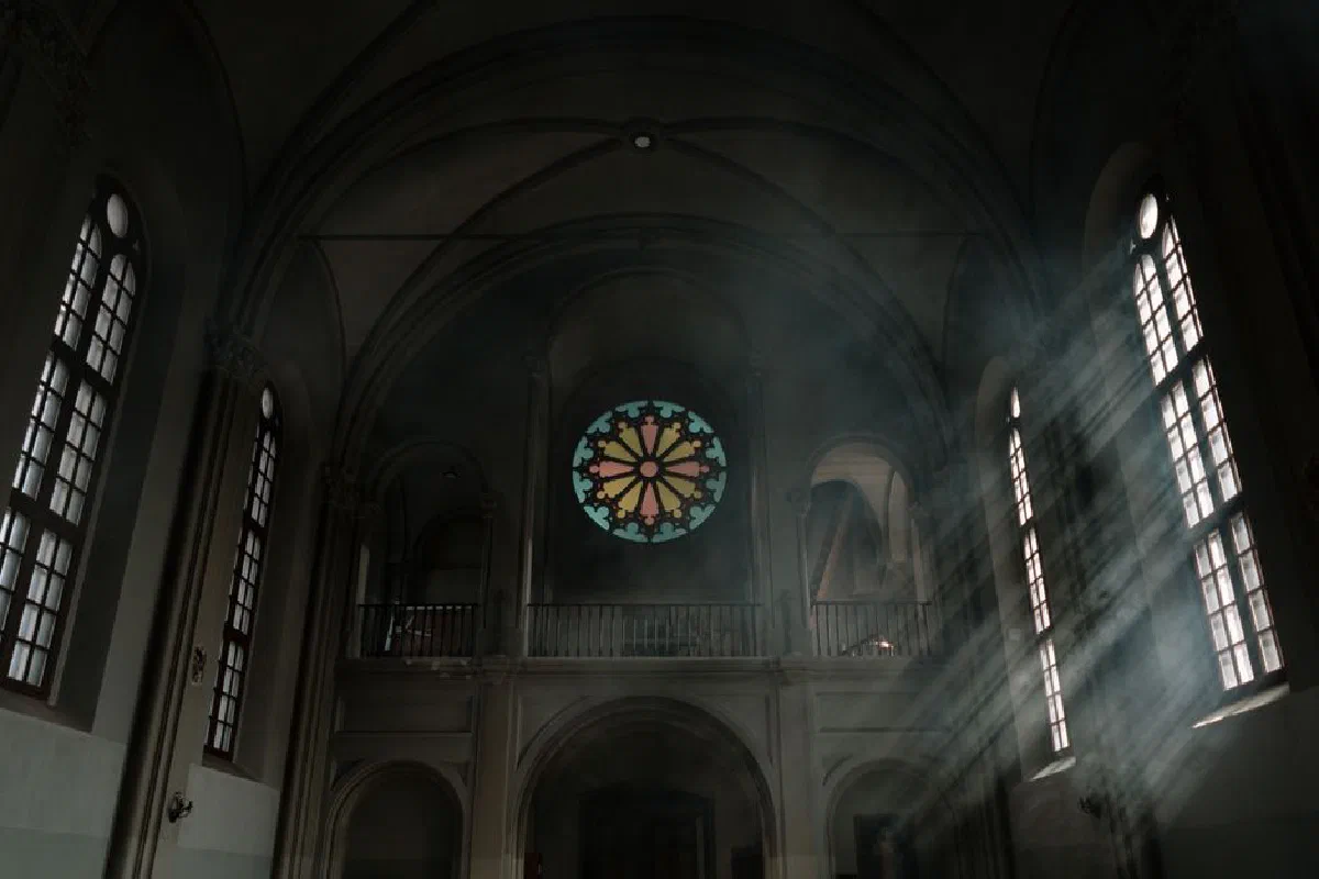 Sunrays streaming through stained glass windows inside a historical church, creating a serene ambiance.
