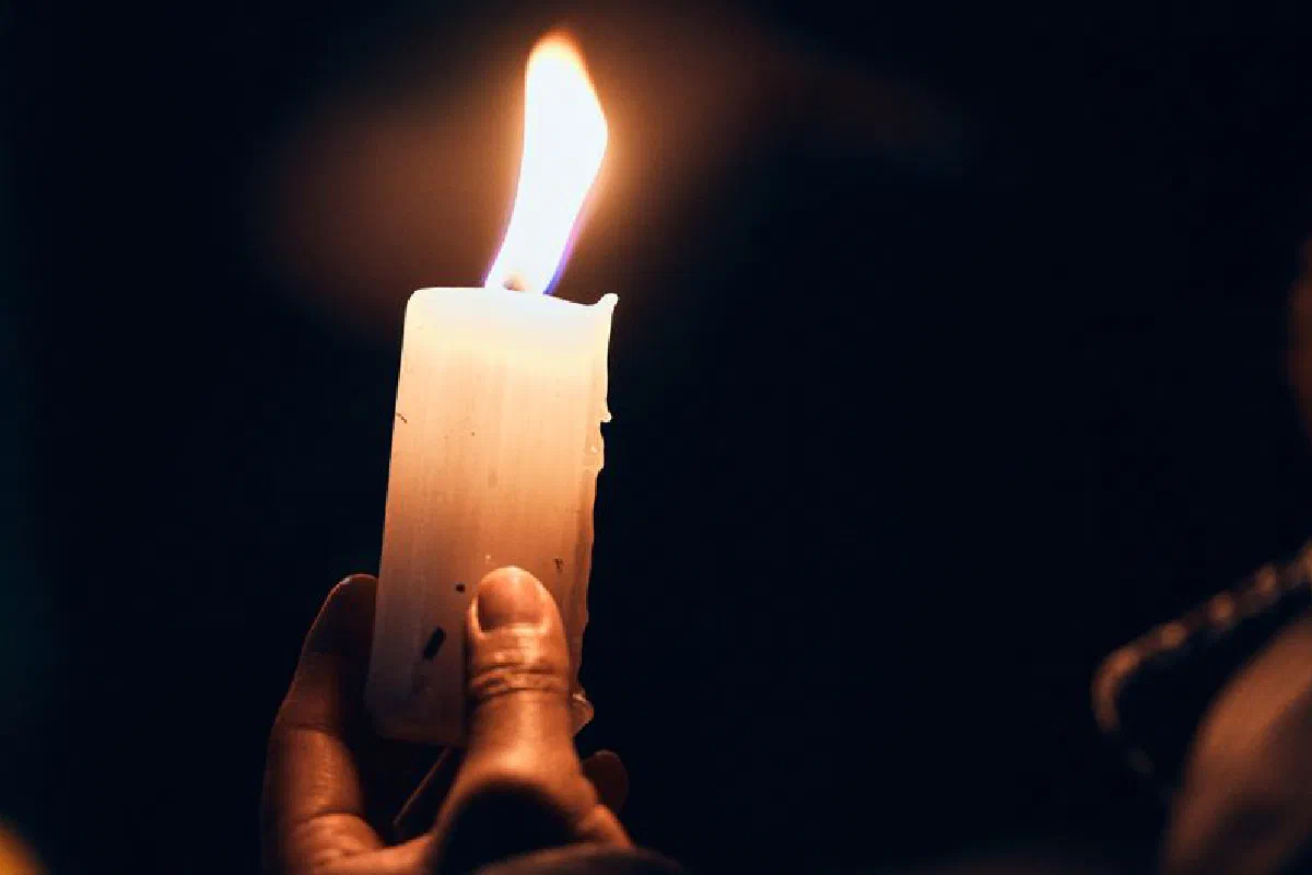 A serene candle flame burns bright against a dark background, creating a warm and peaceful ambiance.