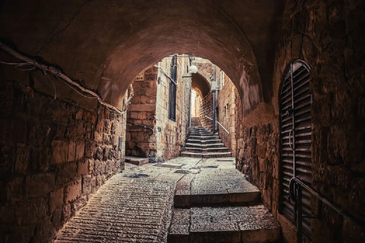 A narrow, stone-paved street in the historic Old City of Jerusalem, Israel.