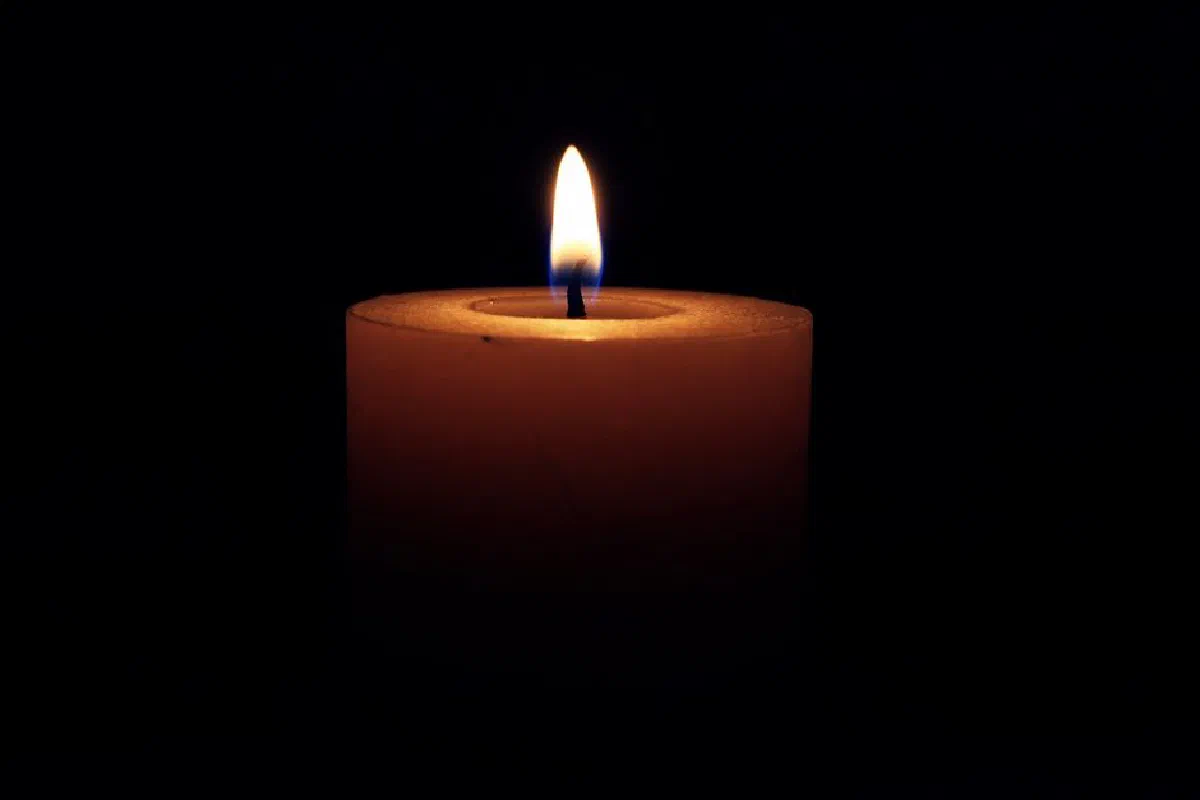 A single candle flame glowing warmly against a dark background.