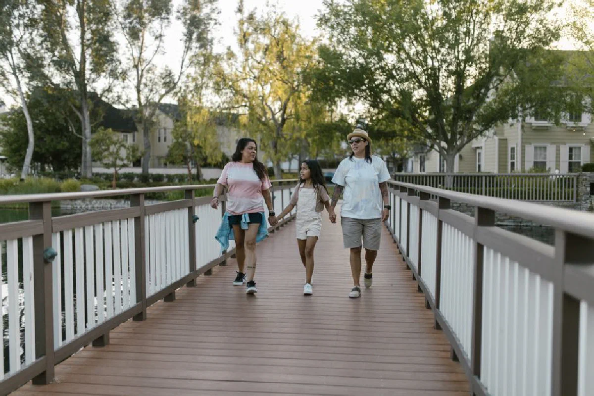 A joyful family enjoying a summer walk on a scenic bridge, holding hands and smiling.