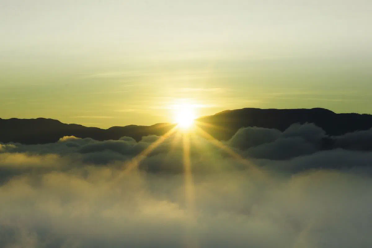 A beautiful sunrise over misty mountains with dazzling sunbeams breaking through the fog.