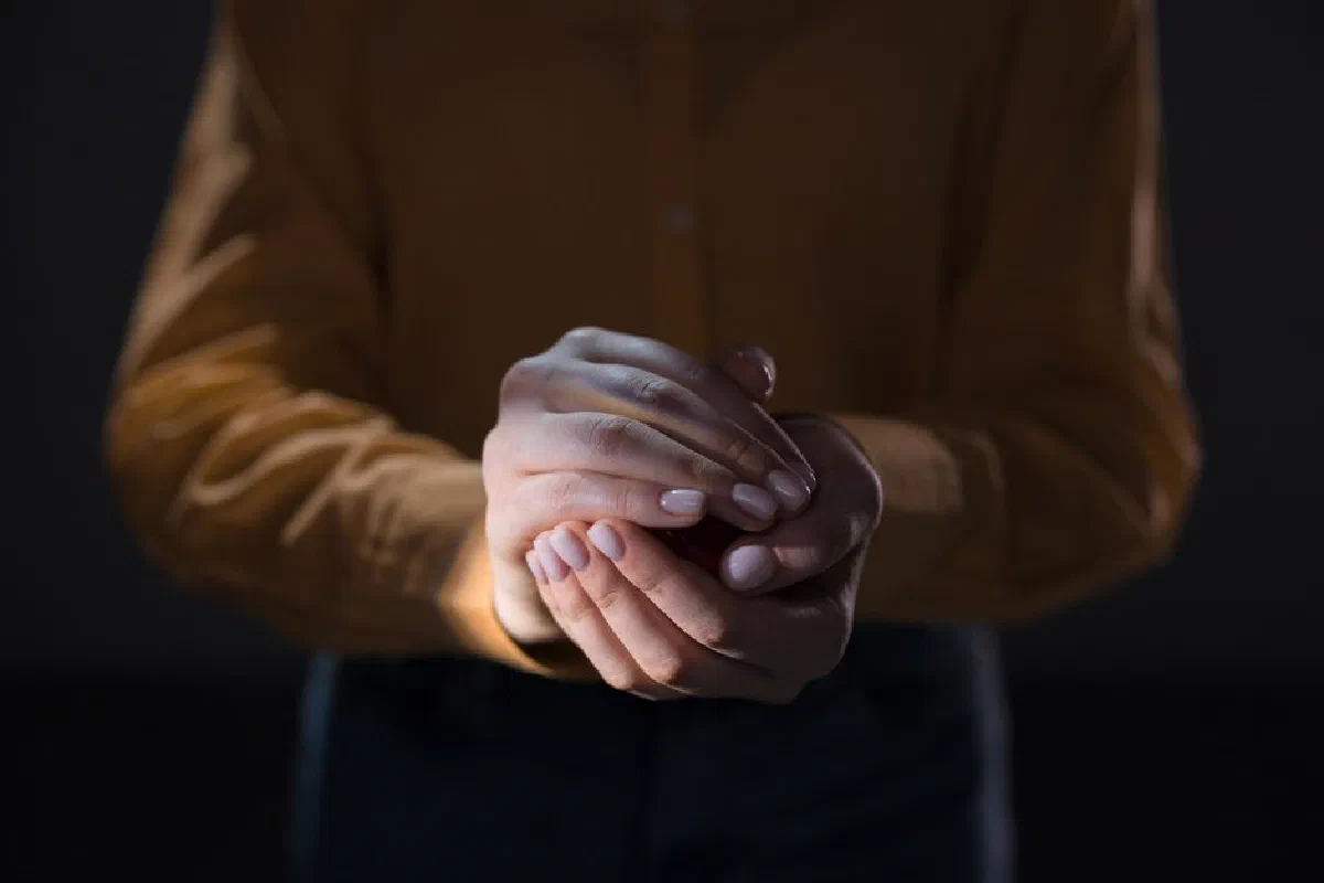 A close-up of hands cupped together with subtle lighting and manicured nails.