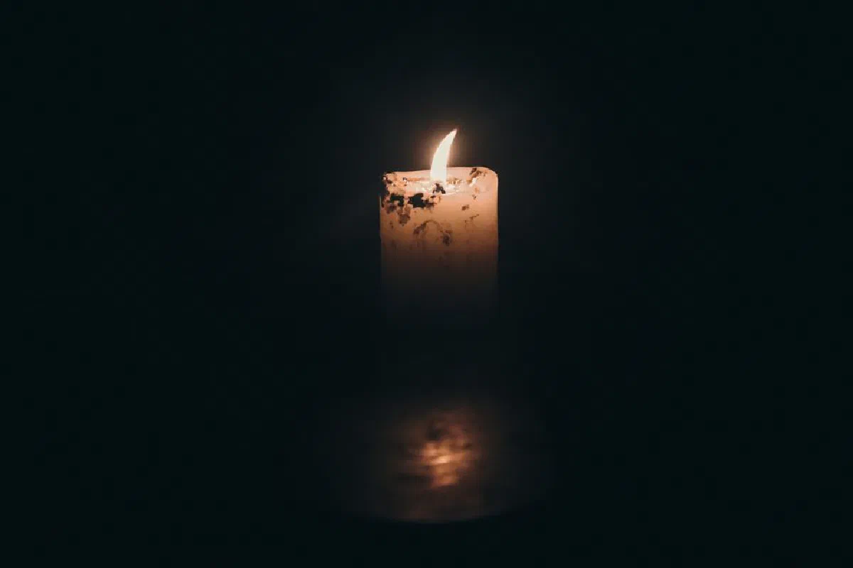 A close-up of a candle flame glowing warmly in dark surroundings, creating a moody atmosphere.