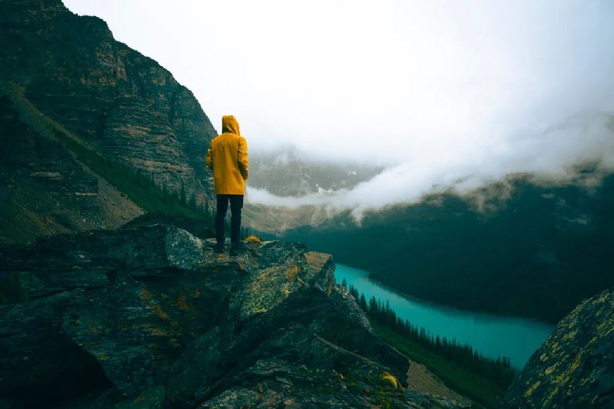 Person in yellow raincoat admires scenic view of Moraine Lake, Banff National Park.