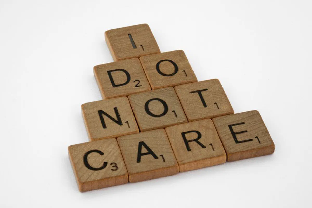 Wooden scrabble tiles arranged to spell 'I Do Not Care' on a clean white surface.