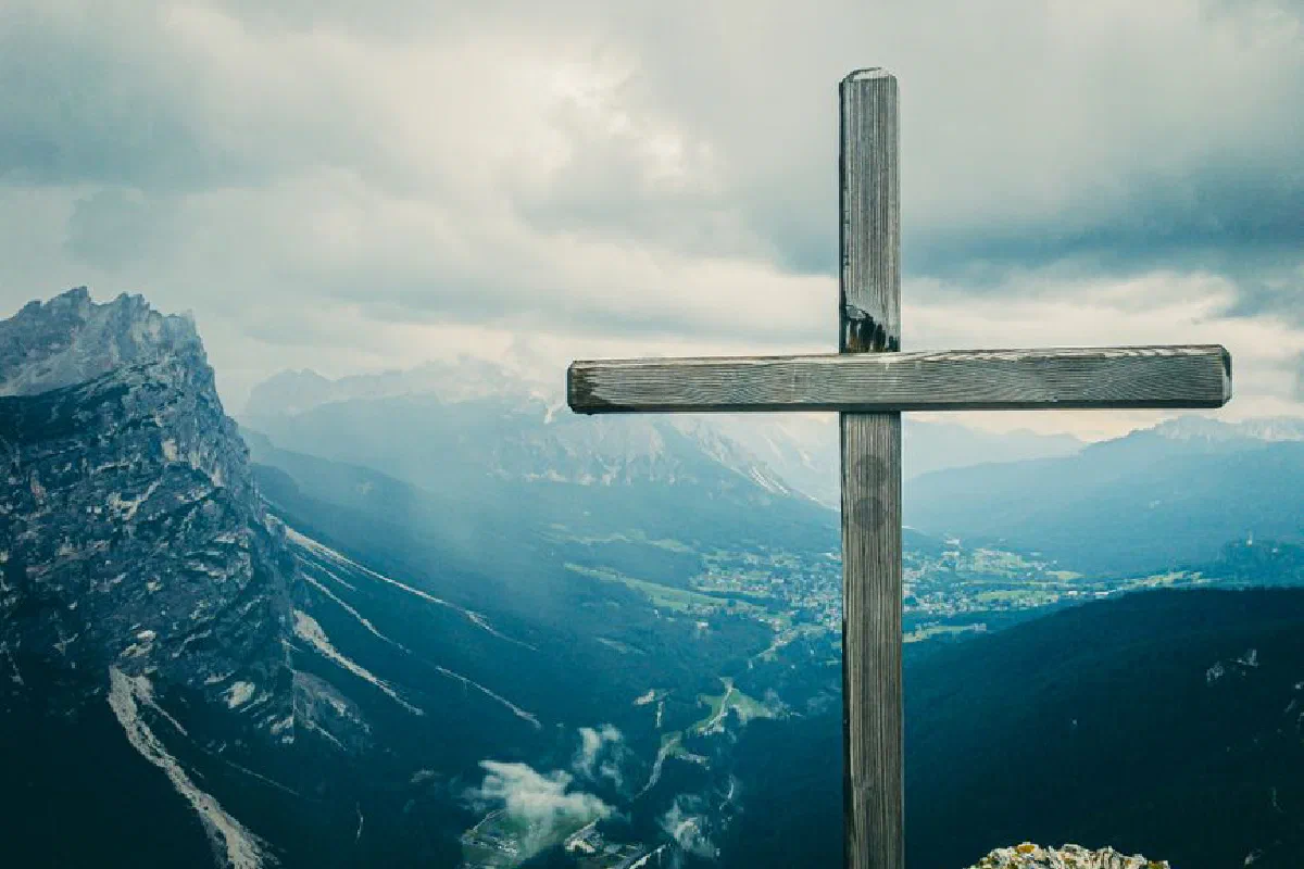 Majestic view of a wooden cross on a mountain peak in Cortina d’Ampezzo with dramatic skies.