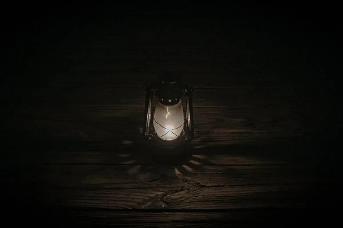 A glowing antique lantern casting light on a dark wooden floor.