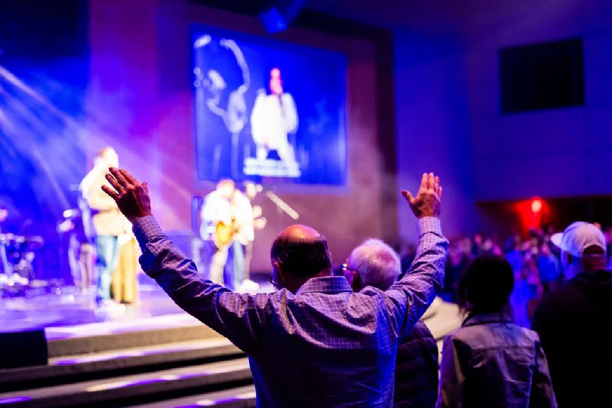 Energetic live concert scene with audience raising hands in vibrant lighting.