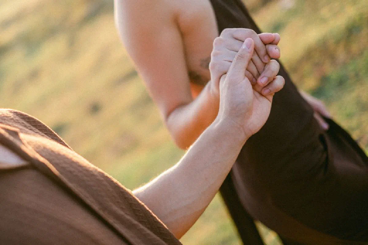 A romantic close-up of two adults holding hands in an outdoor setting, conveying love and connection.