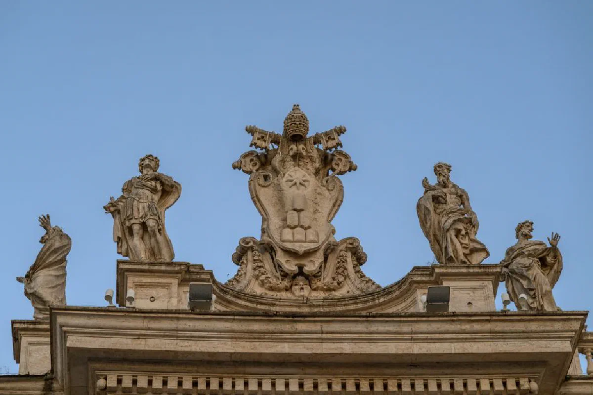 A detailed view of St. Peter's Basilica statues in Vatican City against a clear blue sky.