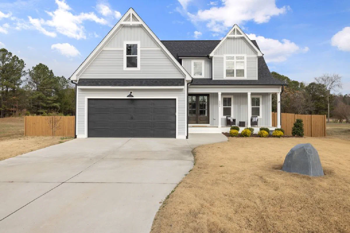 Charming two-story suburban house with black garage and cozy porch.