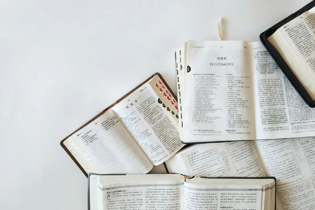 Multiple Bibles open on a white background showing text from Ecclesiastes in different languages.