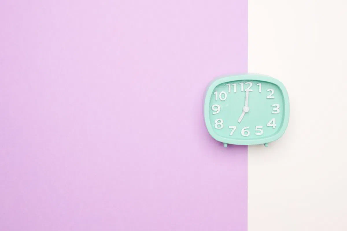 A pastel blue alarm clock on a purple and white split background, showcasing minimalist design.